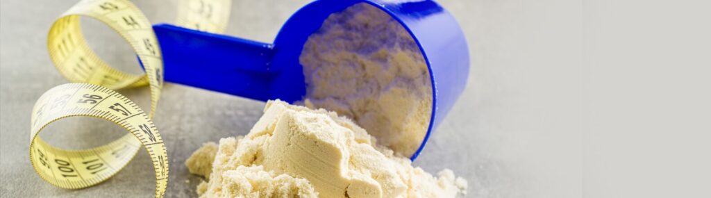 Foto em close de um medidor derramando whey sobre uma superfície - como preparar Whey Protein?