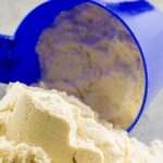 Foto em close de um medidor derramando whey sobre uma superfície - como preparar Whey Protein?
