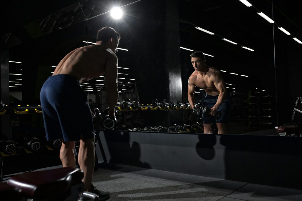 Atleta em preparação física intensa, refletindo os critérios de proporção, condicionamento e apresentação exigidos nas diferentes categorias do fisiculturismo.