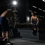 Atleta em preparação física intensa, refletindo os critérios de proporção, condicionamento e apresentação exigidos nas diferentes categorias do fisiculturismo.