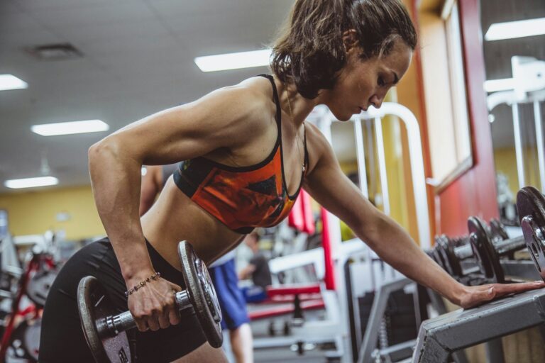 Mulher realizando exercício de força na academia como preparação para campeonatos de fisiculturismo feminino.