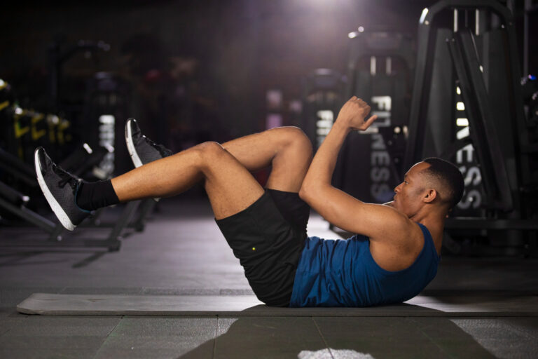 Homem executando abdominal com pernas elevadas em academia, exemplo de treino voltado para fortalecimento do core e redução de gordura corporal.