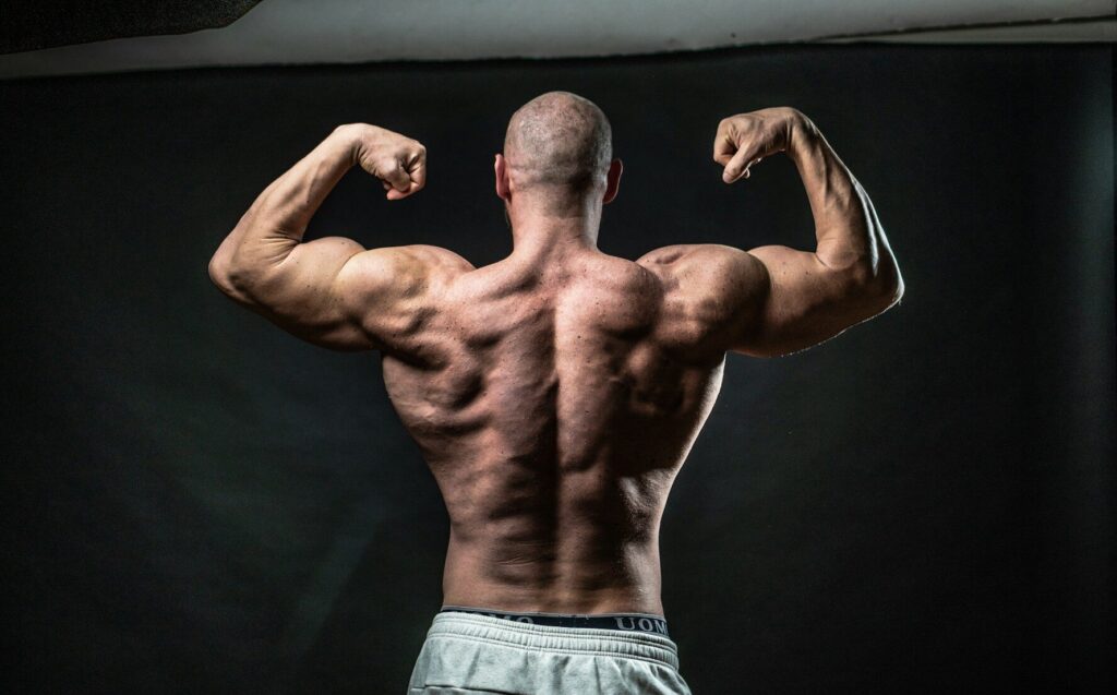 Homem exibindo desenvolvimento dos músculos das costas, resultado do fortalecimento dorsal com exercícios como a remada baixa no treino de musculação.