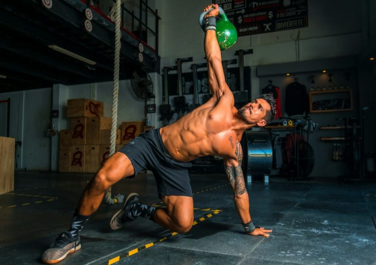 Atleta executando levantamento com kettlebell em sessão de treino full body, método que estimula todos os grupos musculares, promovendo ganhos de força e hipertrofia.