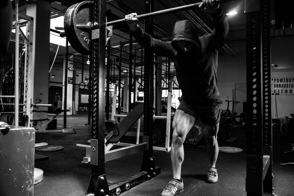 Atleta realizando agachamento com barra em treino de força na academia, representando a superação do efeito platô e a busca por evolução muscular.