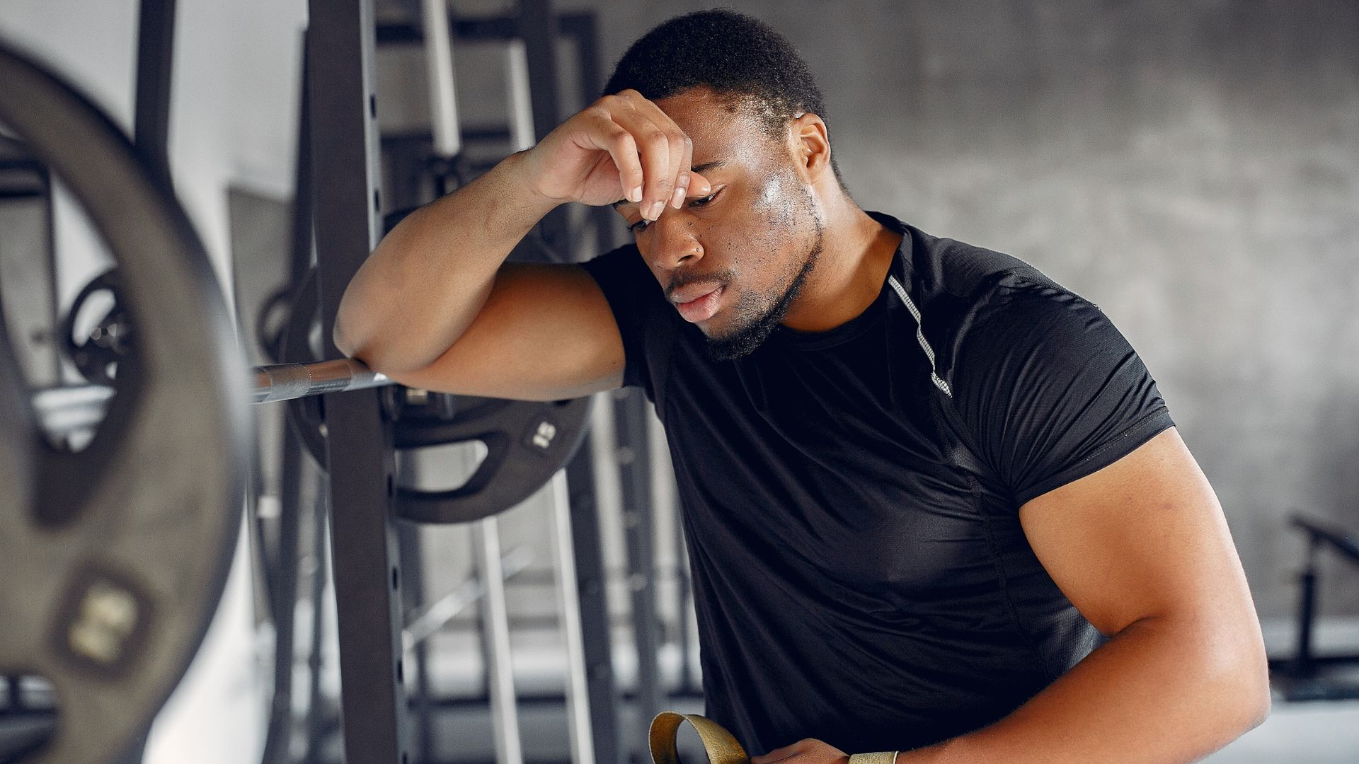 Para que serve a arginina e quem deve tomar? 1 Homem descansando após o treino na academia, demonstrando fadiga muscular enquanto cogita usar arginina para melhorar seu desempenho e recuperação.
